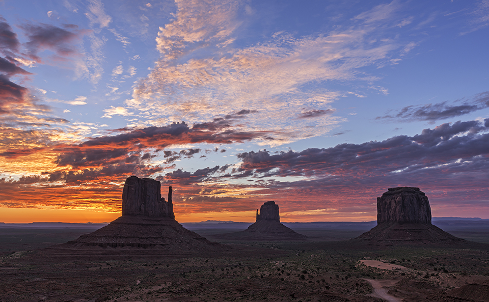 Monumental Sunrise; West Mitten; East Mitten; Merrill Butte; daybreak; monument valley; dawn; sunrise; sandstone buttes; colorful; fiery; explode; dark; light; contrast; orange; bright; clouds; weather; navajo nation; arizona; utah; desert southwest; formation; and; the; over; with; under; above; against; in the; on the; at the; Loree Johnson
